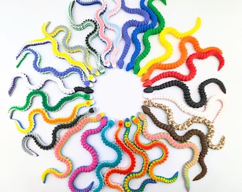 May include: A circular arrangement of brightly coloured snake toys. The snakes are in a variety of colours, including blue, green, yellow, red, and pink, with some patterned. The toys are made of a soft, bendable material, and are suitable for children.