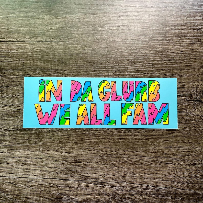 May include: A light blue sticker with the text "IN DA CLUB WE ALL FAM" in colorful, wavy letters.