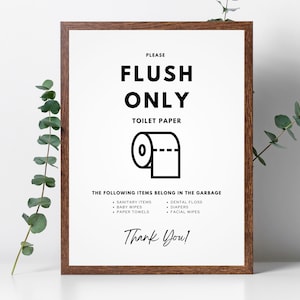 May include: A framed bathroom sign with the text "PLEASE FLUSH ONLY TOILET PAPER" and a graphic of a toilet paper roll. Below, a list of items to discard in the trash. The sign is in a brown wooden frame.