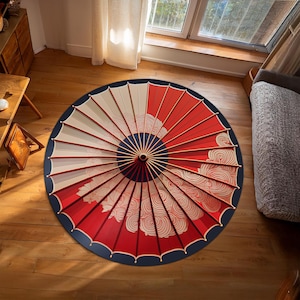 May include: A red and white Japanese-style umbrella with a blue border and a swirling cloud pattern. The umbrella is lying flat on a wooden floor.