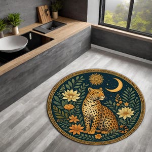 Pode incluir: Tapete oval com uma ilustração detalhada de um leopardo, flores, um sol e uma lua crescente. O tapete tem um fundo azul escuro e uma borda dourada. O leopardo é bege com manchas pretas.