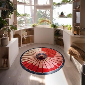 May include: A red and white round rug with a blue and gold umbrella design. The rug is in a room with white walls and wooden shelves.