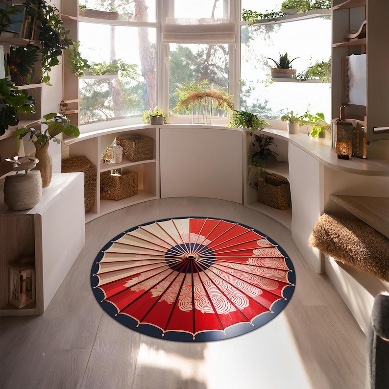 May include: A red and white round rug with a blue and gold umbrella design. The rug is in a room with white walls and wooden shelves.