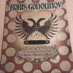 Op de afbeelding: Een vintage programma voor een uitvoering van Boris Godoenov door de Opera Russe de Paris. De omslag toont een gouden en zwarte dubbelkoppige adelaar met een kroon en een rode achtergrond met gouden stippen.