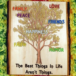 May include: A wooden sign with a tree illustration and the words "The Best Things In Life Aren't Things." The tree has branches with the words "Love", "Family", "Peace", "Friends", "Happiness", "Faith", and "Humor" written on them.