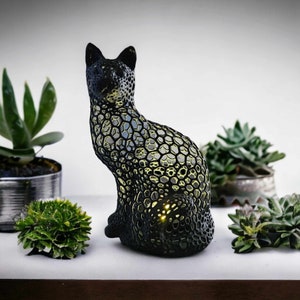 May include: A black cat-shaped lamp with a honeycomb design. The lamp is lit and glows yellow.