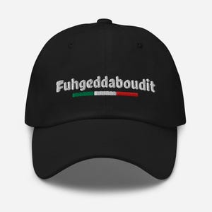 May include: Black baseball cap with the embroidered phrase "Fuhgeddaboudit" in white, above a green, white, and red stripe. The cap has a curved brim and a fabric strap closure.
