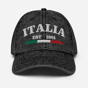 Op de afbeelding: Zwarte distressed denim baseballcap met witte geborduurde tekst "ITALIA EST 1861" en een groene, witte en rode Italiaanse vlag.
