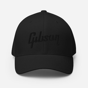 May include: Black baseball cap with the embroidered word "Gibson" in a script font. The cap has a curved brim and a structured fit. The hat is made of a soft, durable material and is suitable for everyday wear.