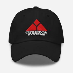 May include: Black baseball cap featuring a red and white embroidered logo. The logo reads "CYBERDYNE SYSTEMS" and features a red triangle design. The cap has a curved peak and a button on the crown.