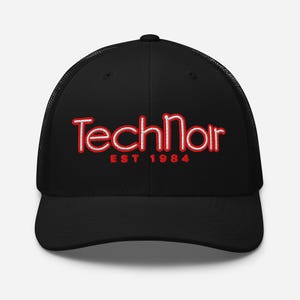 Puede incluir: Una gorra de camionero negra con un diseño bordado en la parte frontal. El texto dice TechNoir en una fuente blanca estilizada con un borde rojo, situado sobre el texto rojo EST 1984. La gorra tiene un panel frontal estructurado y malla.