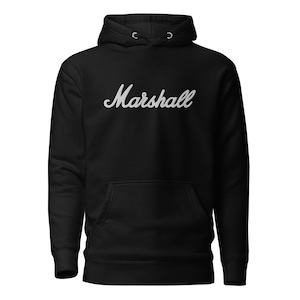 May include: Black hoodie with the word "Marshall" in a white, cursive font across the chest. The hoodie has a drawstring hood and a front pocket. The garment is made of a soft material.