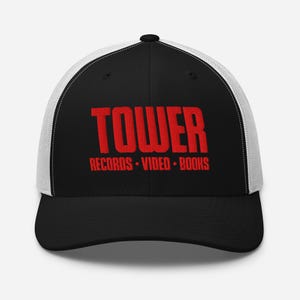 May include: Black and white trucker hat with the word "TOWER" in red, along with "RECORDS • VIDEO • BOOKS" in red. The hat has a black front panel and brim, with a white mesh back.