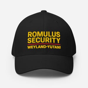 Könnte beinhalten: Schwarze Baseballkappe mit dem Text "ROMULUS SECURITY" in Gelb, einer roten Linie und "WEYLAND-YUTANI" in Gelb. Die Kappe hat einen gebogenen Schirm und eine strukturierte Passform.