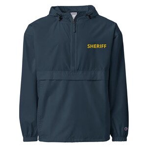 May include: A navy blue hooded jacket with a zipper closure and a yellow embroidered "SHERIFF" logo on the front.