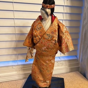 VINTAGE GEISHA GIRL figurine with mask.Brocade dress and paper fan on original display base.16.5&quot;tall