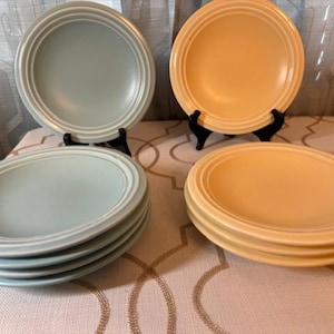 May include: A set of three ceramic nesting bowls in shades of blue, green, and white. The bowls feature a speckled glaze and a simple, modern design. The largest bowl measures approximately 7 inches in diameter.