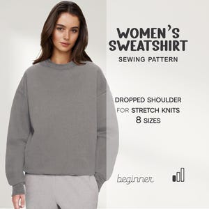 Könnte beinhalten: Eine Person trägt ein graues Sweatshirt und eine graue Jogginghose. Das Bild enthält den Text "WOMEN'S SWEATSHIRT SEWING PATTERN" und "DROPPED SHOULDER FOR STRETCH KNITS 8 SIZES". Das Wort "beginner" ist ebenfalls sichtbar.