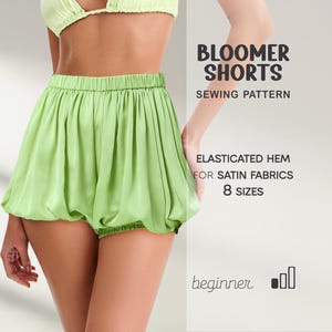 May include: Light green satin bloomer shorts with an elasticated hem. The image includes the text "BLOOMER SHORTS SEWING PATTERN" and "ELASTICATED HEM FOR SATIN FABRICS 8 SIZES". The shorts are part of a beginner sewing pattern.