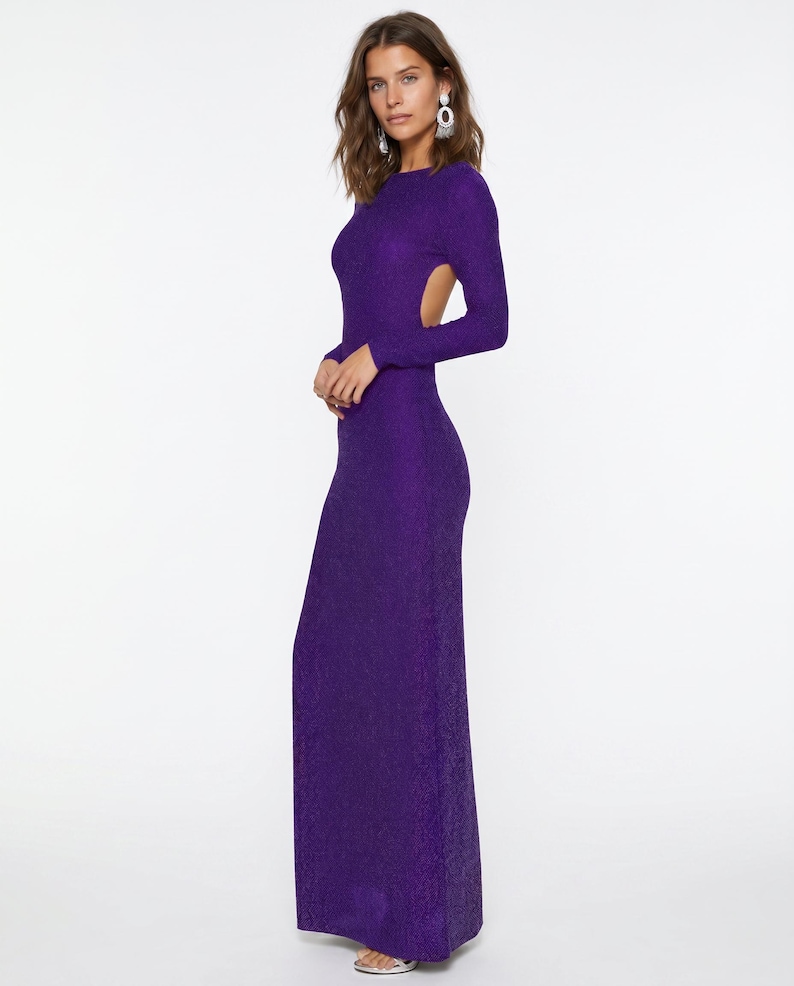 May include: A long, form-fitting, purple dress with long sleeves and an open back. The dress has a textured appearance and a floor-length hemline. The model is wearing silver earrings.