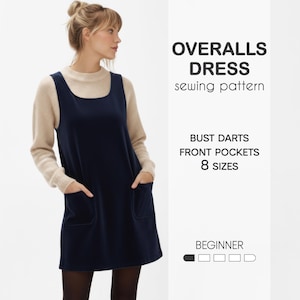 Könnte beinhalten: Eine Frau trägt ein marineblaues Latzkleid mit Vordertaschen. Das Kleid wird mit einem beigen Pullover kombiniert. Der Text lautet "OVERALLS DRESS sewing pattern" und listet Merkmale wie "BUST DARTS" und "8 GRÖSSEN".