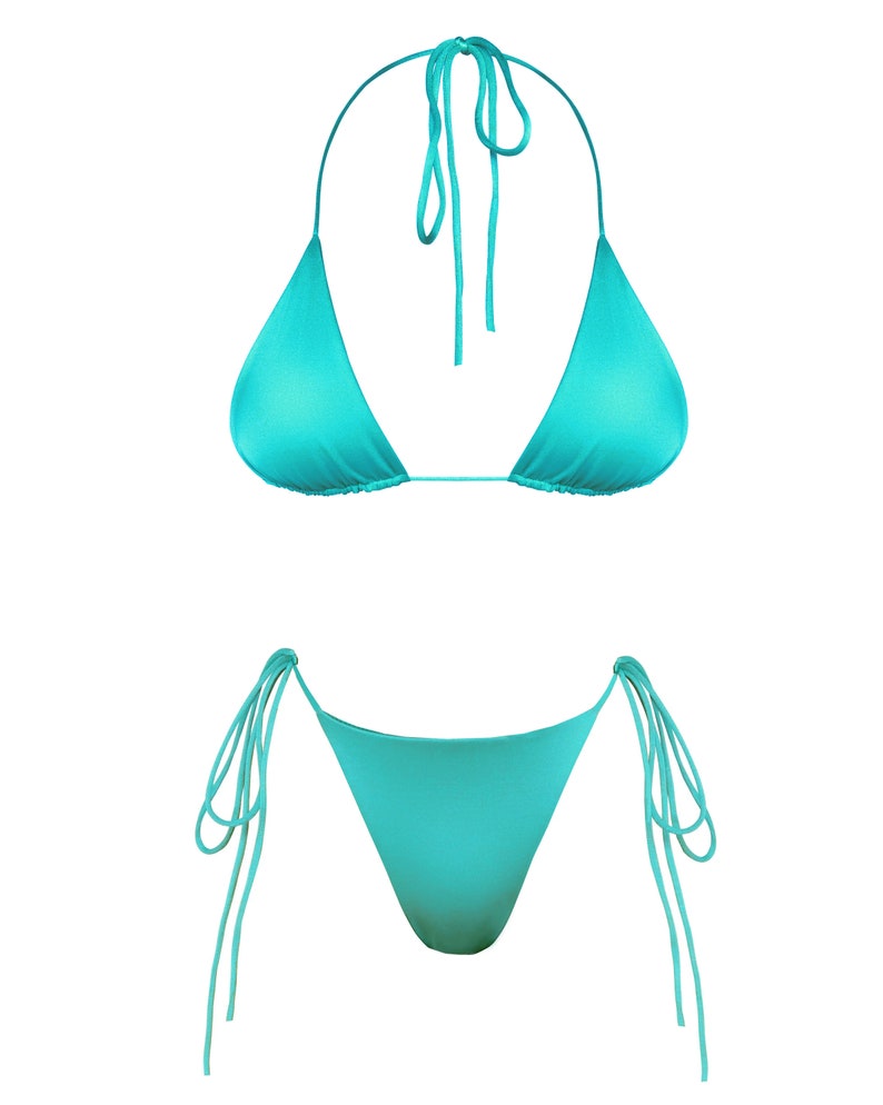 Puede incluir: Conjunto de bikini turquesa. La parte superior es de estilo triangular con lazos en el cuello. La parte inferior es de corte cl&aacute;sico con lazos laterales. La tela tiene un ligero brillo. El conjunto se muestra sobre un fondo blanco.