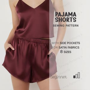 May include: Burgundy satin pajama shorts and matching camisole. The shorts have side pockets and an elastic waistband. The image also includes text that says "PAJAMA SHORTS SEWING PATTERN" and "WITH SIDE POCKETS FOR SATIN FABRICS 8 SIZES".