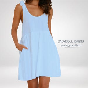 May include: A light blue babydoll dress with thin straps that tie at the shoulders. The dress has a scoop neckline and a gathered skirt. The dress is shown on a model.