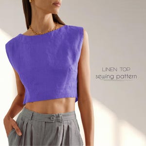 May include: A purple linen top sewing pattern. The pattern is shown on a model wearing a grey skirt.