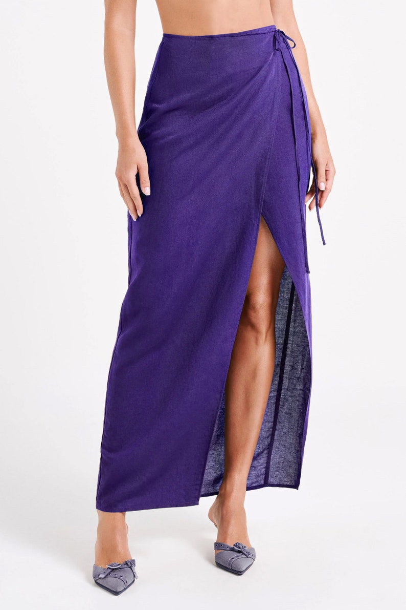 May include: A long, purple wrap skirt with a thigh-high slit and a tie closure at the waist.