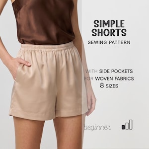 May include: Tan-colored shorts with an elastic waistband and side pockets. The shorts are part of a sewing pattern labeled "Simple Shorts" with the text "With side pockets for woven fabrics" and "8 sizes". The model is wearing a brown top.