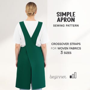 May include: A green apron with crossover straps, worn over a white t-shirt. The apron is part of a sewing pattern for woven fabrics, available in three sizes. Text on the image reads "SIMPLE APRON SEWING PATTERN" and "beginner".
