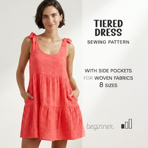 May include: A coral-colored tiered dress with side pockets, featuring a scoop neckline and tie straps. The dress is made for woven fabrics and is available in 8 sizes. The image also includes text that says "TIERED DRESS SEWING PATTERN".