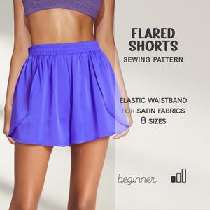 Op de afbeelding: Een naaipatroon voor uitlopende shorts in helderblauw. De afbeelding toont de shorts met een elastische tailleband, ontworpen voor satijnen stoffen. Het patroon is verkrijgbaar in 8 maten en is geschikt voor beginners. Tekst op de afbeelding luidt: "Flared Shorts Sewing Pattern".