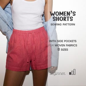 May include: Coral-colored shorts with side pockets and a drawstring waist. The shorts are part of a sewing pattern for woven fabrics, with the text "WOMEN'S SHORTS SEWING PATTERN" and "8 SIZES". The model is wearing a white tank top and a light blue button-down shirt.