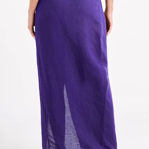 May include: A long purple skirt with a side slit. The skirt is made of a lightweight fabric and has a simple, elegant design.