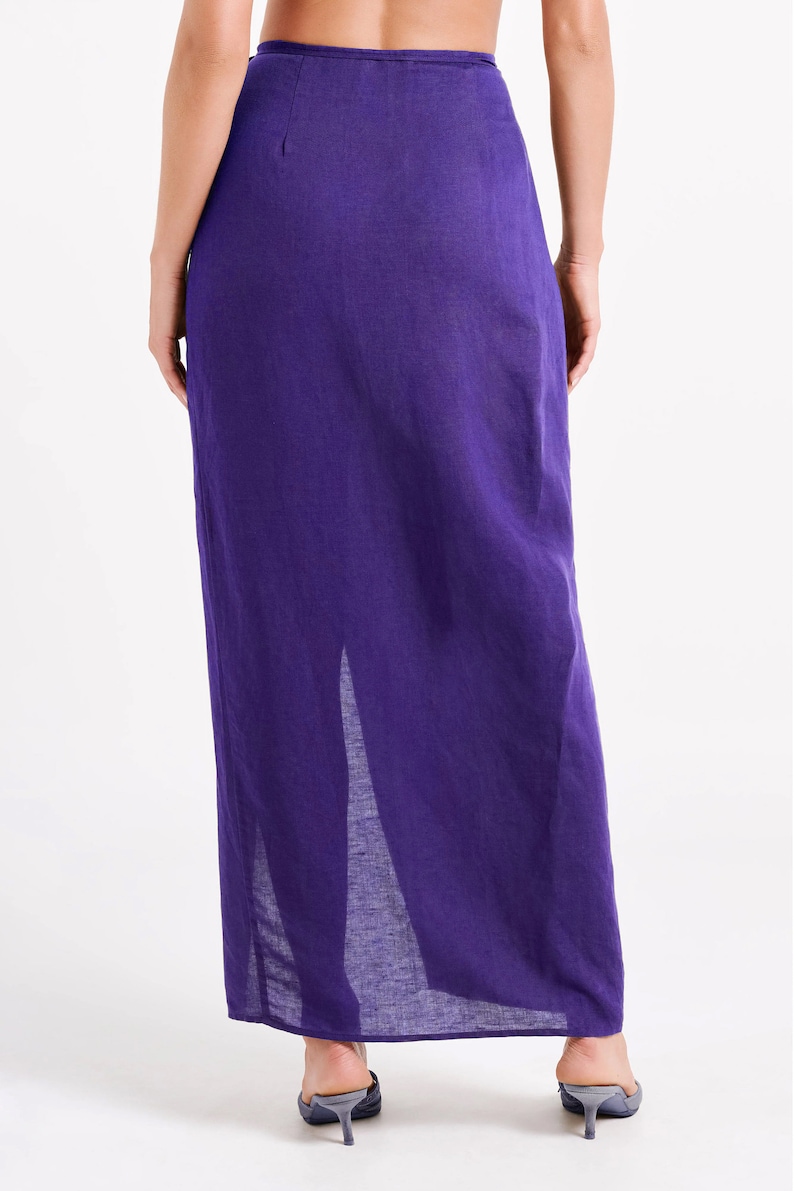 May include: A long purple skirt with a side slit. The skirt is made of a lightweight fabric and has a simple, elegant design.