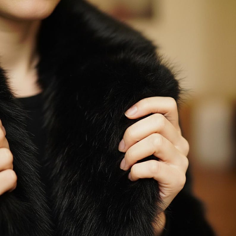 May include: Close-up of a black fur coat with a plush, textured appearance. The coat's collar is prominent, and the fur appears soft and luxurious. The image highlights the coat's rich color and texture.
