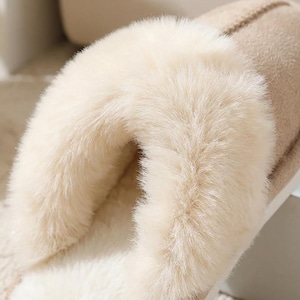 Peut inclure: Gros plan sur une pantoufle beige avec une doublure en fausse fourrure cr&egrave;me et moelleuse. La pantoufle a un ext&eacute;rieur doux semblable &agrave; du daim et une conception confortable et coussin&eacute;e. L'accent est mis sur la texture moelleuse et invitante de la pantoufle.