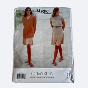 May include: A vintage Vogue Patterns sewing pattern featuring Calvin Klein designs. The cover displays two models wearing a blazer and dress ensemble. The pattern number is 1069, and the size range is 14-16-18.