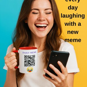 Puede incluir: Una taza blanca con interior y asa rojos, con el texto "DAILY MEME", un código QR y un emoji riendo. La imagen también incluye el texto "Begin every day laughing with a new meme". Una persona sostiene la taza y un smartphone negro.