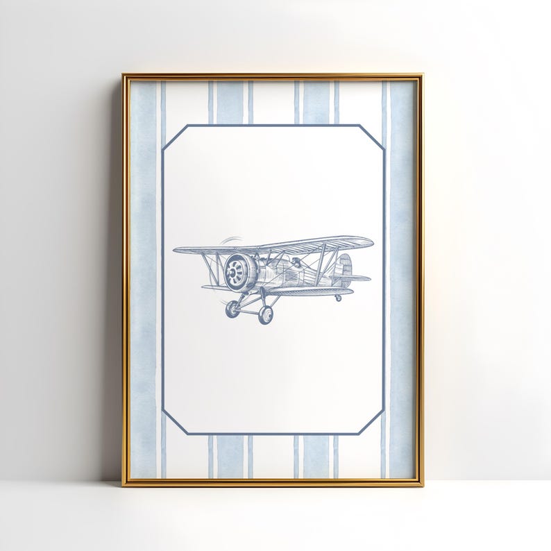 May include: A framed print featuring a blue and white biplane illustration. The artwork is set against a white background with a blue striped border and a gold frame. The biplane is detailed with propeller and wheels.