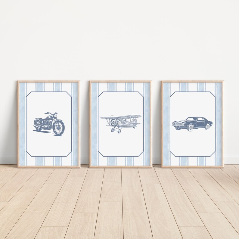 May include: Three framed prints featuring vintage vehicles: a motorcycle, a biplane, and a classic car. Each print has a blue and white striped border and a light wood frame. The illustrations are in shades of blue.
