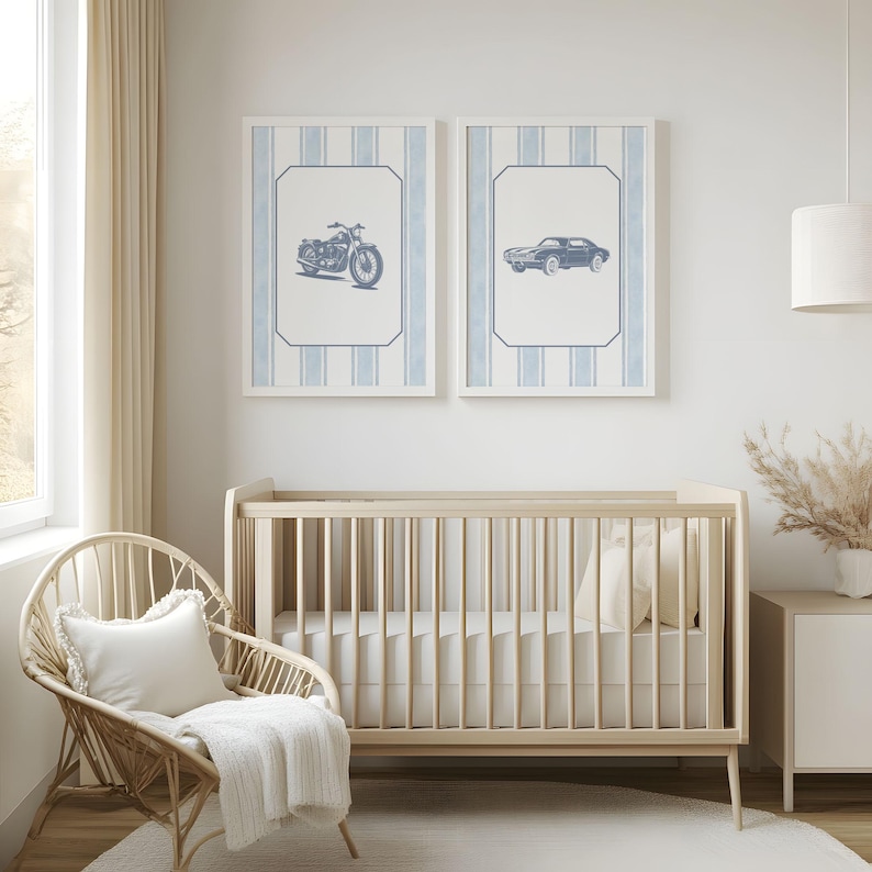 May include: Two framed prints with blue motorcycle and car illustrations hang above a wooden crib. The prints have a white background with blue vertical stripes. A wicker chair with a white pillow and blanket sits nearby, creating a nursery setting.