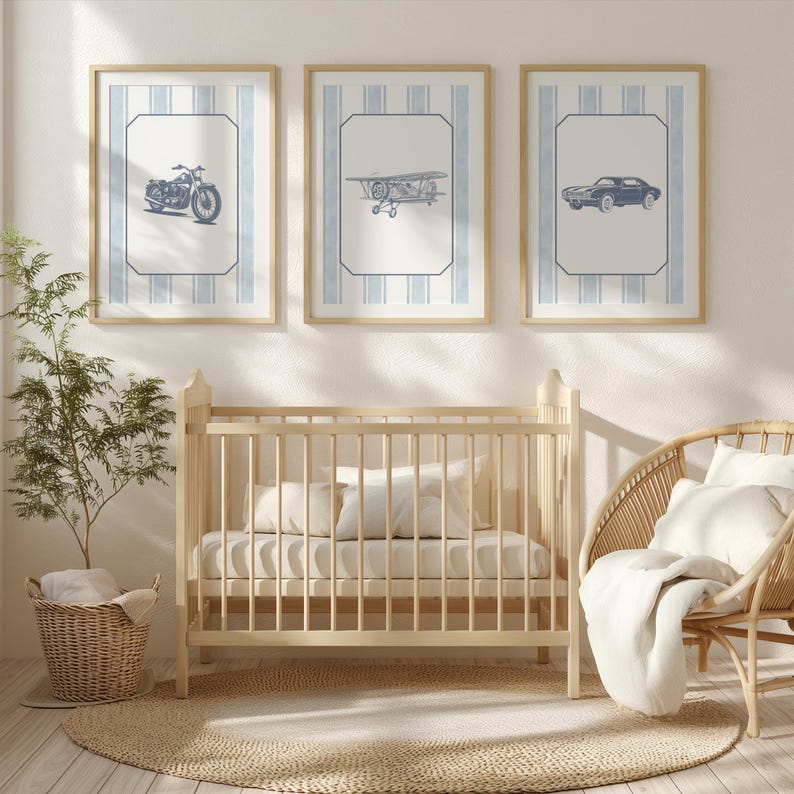 May include: Three framed prints with vintage vehicle illustrations: a motorcycle, airplane, and car. Each print has a blue and white striped background and a light wood frame. A light wood crib, wicker chair, and round rug complete the nursery scene.