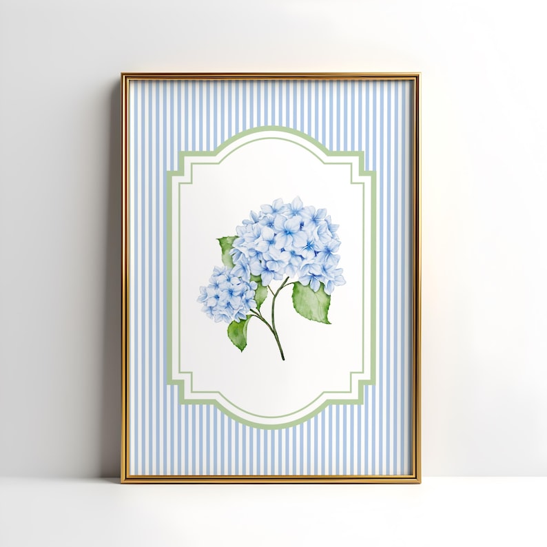 May include: A framed print with a watercolour illustration of blue hydrangea flowers and green leaves. The artwork is set against a white background within a green and white decorative border, and a blue and white striped background. The frame is gold.