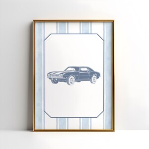 May include: Framed print featuring a blue classic car illustration. The car is centered on a white background with a blue border and a striped blue and white background. The frame is gold.
