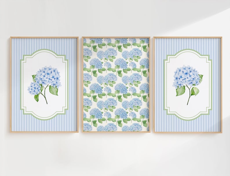 May include: Three framed art prints showcasing blue hydrangea flowers. Two prints have a blue and white striped background with a white and green framed hydrangea. The central print displays a pattern of blue hydrangeas on a white backdrop.