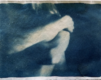 May include: A cyan blue cyanotype print of a blurry image of a person's arm and leg.