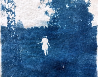 May include: A cyanotype photograph of a person walking through a forest. The person is a silhouette against the blue background. The trees are visible in the background.